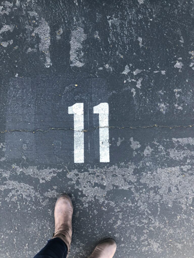 A pair of boots standing on a weathered asphalt surface marked with the number eleven.