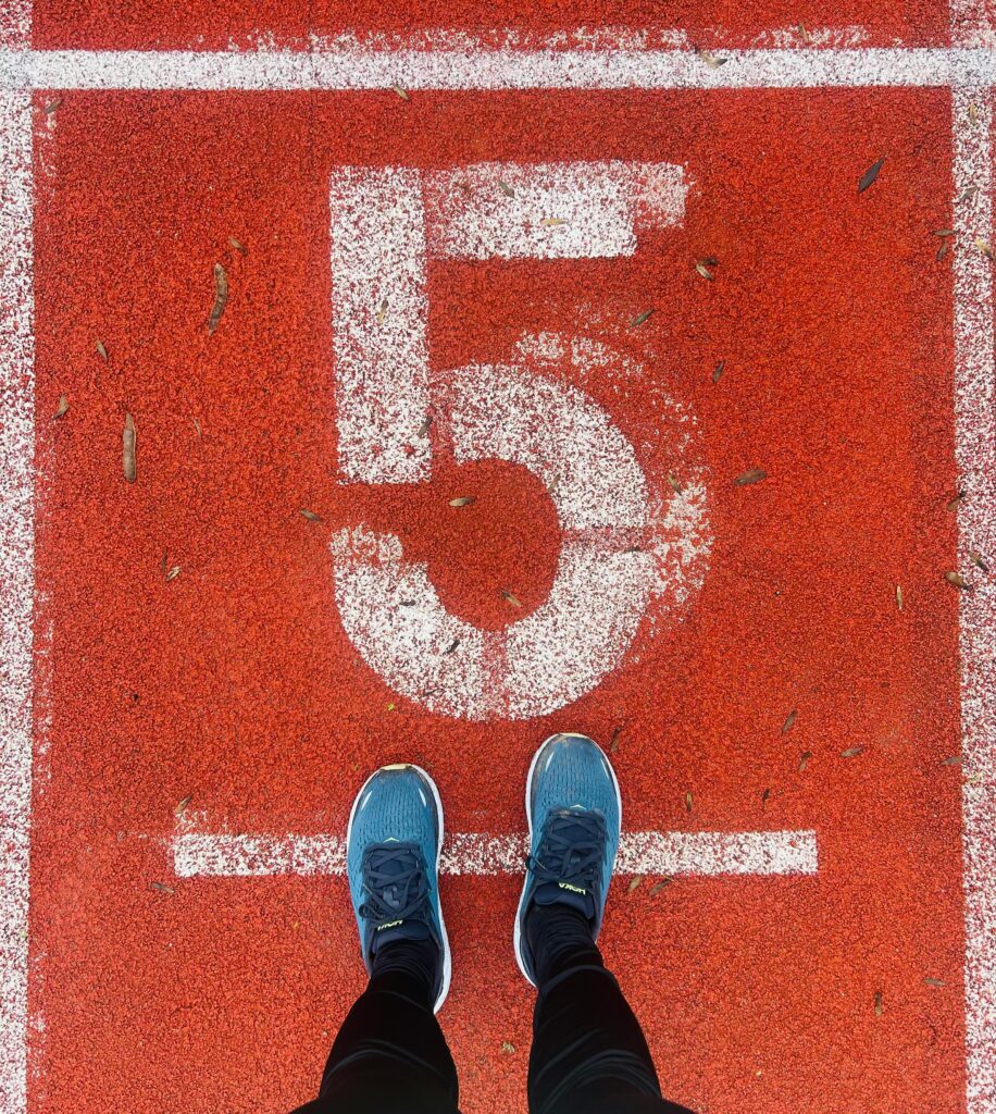 Running shoes on track lane 5, emphasizing fitness and competition.