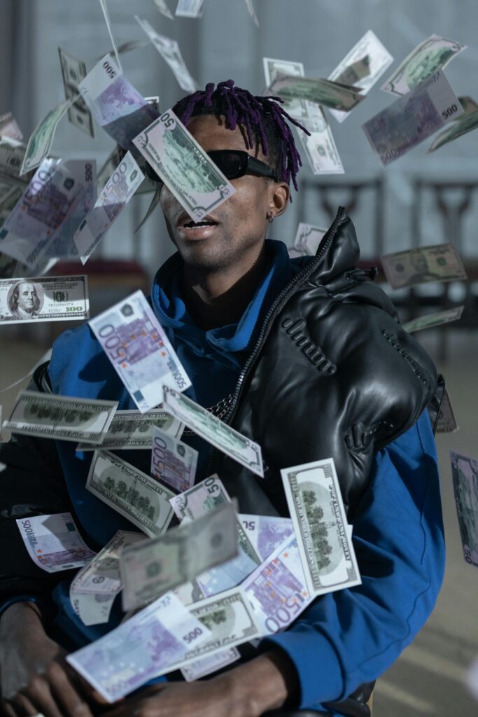 A stylish man with a leather jacket and sunglasses surrounded by floating currency notes.